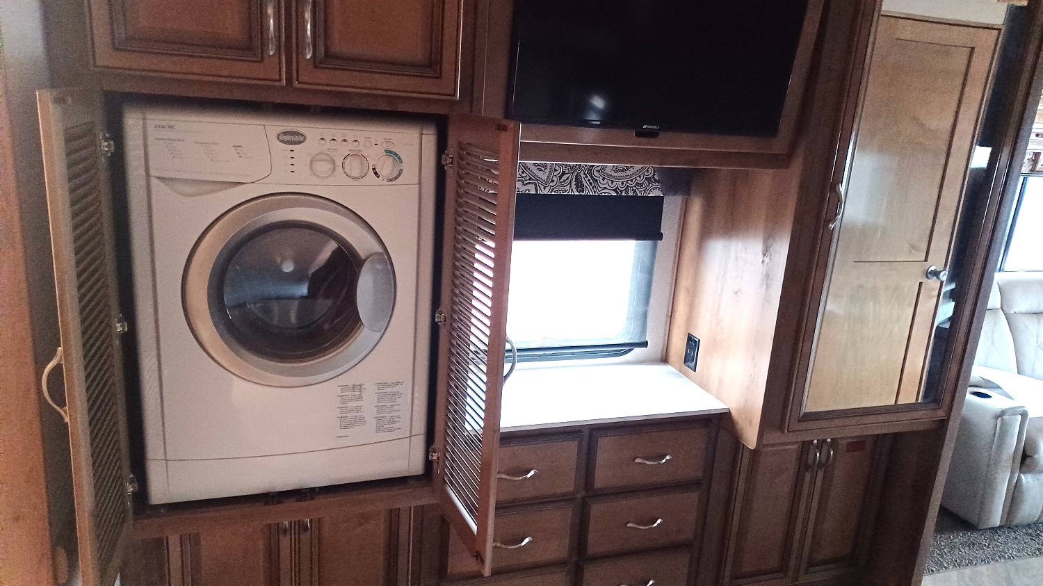 Fleetwood Bounder 35K motorhome with a washer and dryer combo in the closet next to the bedroom entertainment center