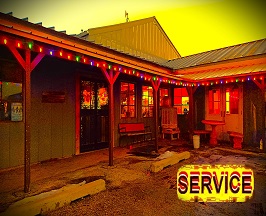 Link to SERVICE with a photo taken at night with filters to make it look brighter than it should showing the front of the building and the Christmas lights lining the long porch of the entry way